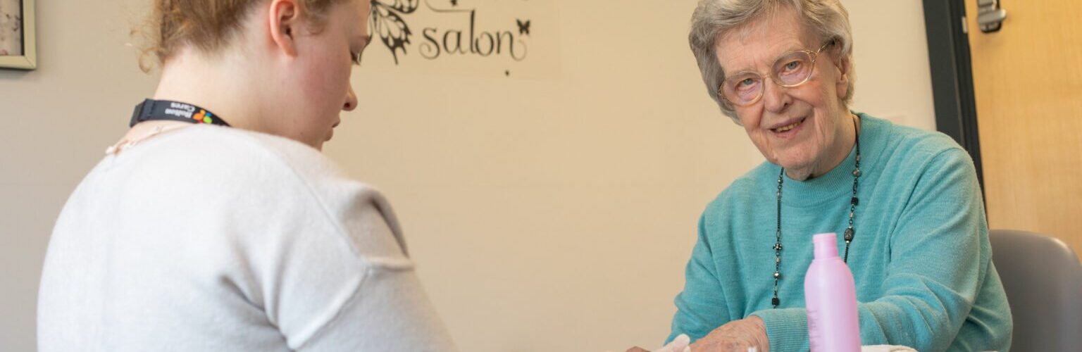 A young carer giving an elderly woman a manicure