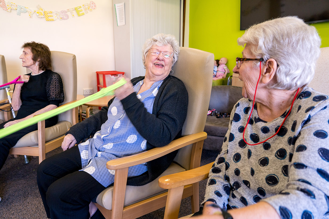 Two elderly women playing a group game and laughing with each other