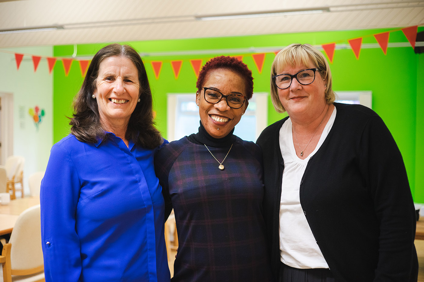 Three staff members gathered together, smiling at the camera