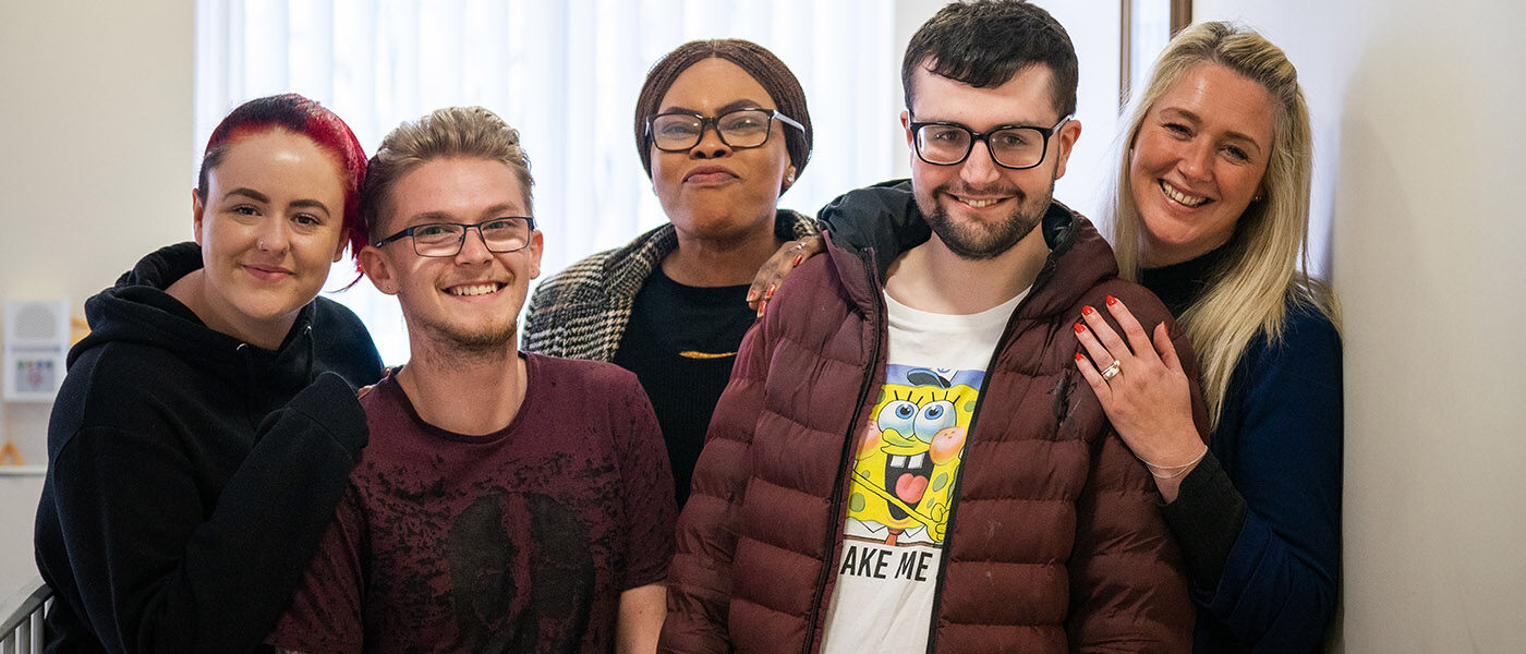 Joshua, at The Hollies, with his care team. They are all smiling at the camera