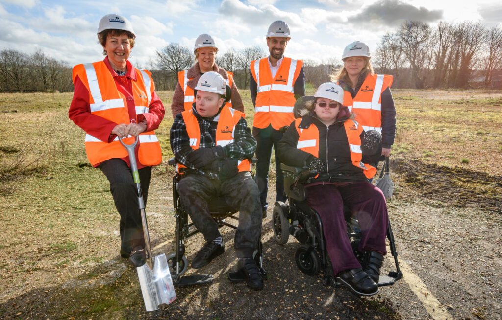 Breaking ground at the new centre - people wearing high visibility outfits and hardhats with shovels, smiling at the camera