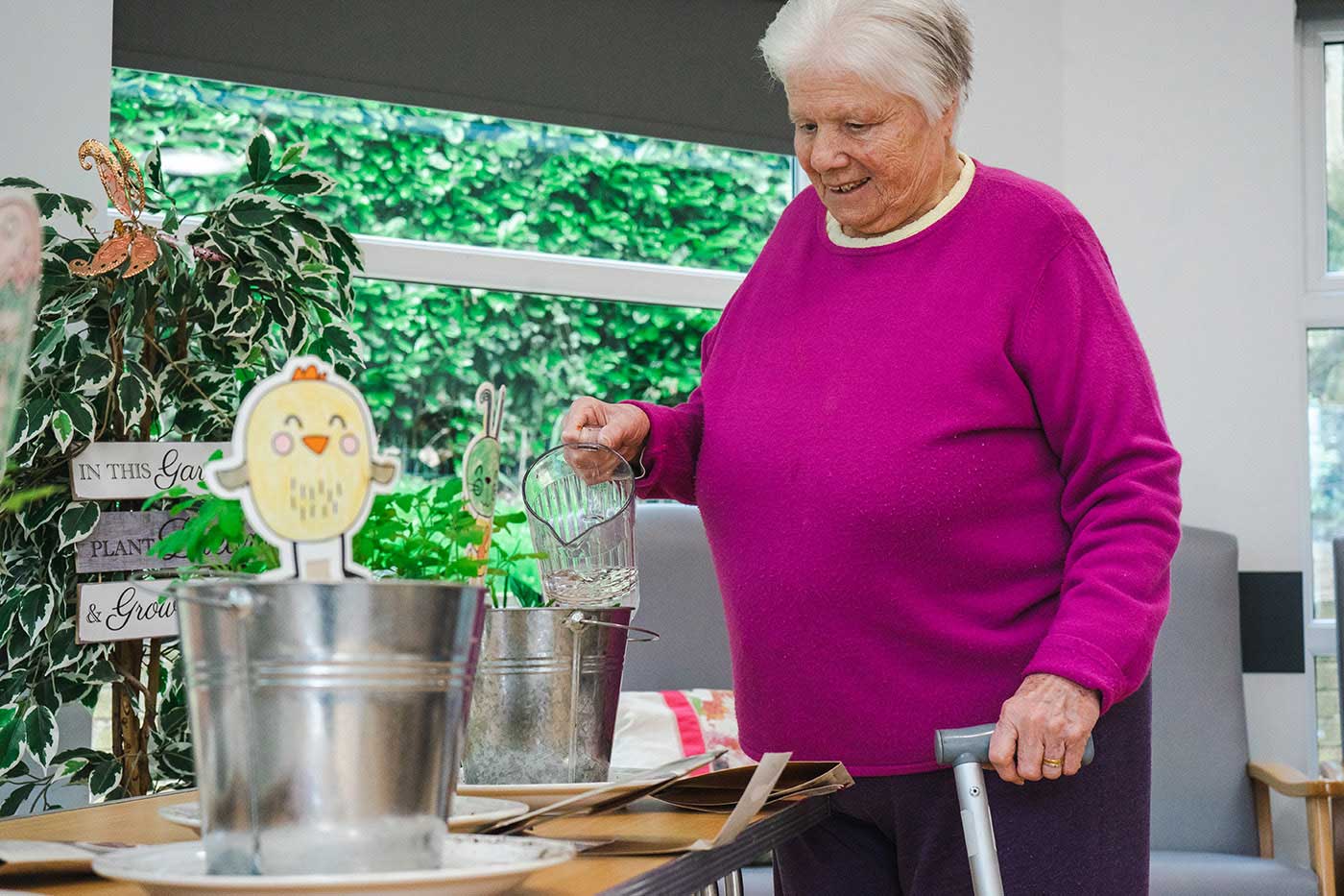 lady pouring a drink, she is wearing a bright coloured top and smiling