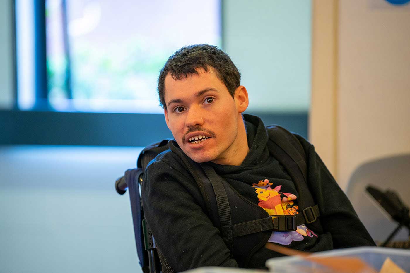 young man in a wheelchair smiling at the camera